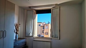 Une pièce avec une fenêtre, un radiateur et un meuble sur lequel est posé un vase.