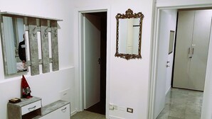 Une pièce spacieuse avec un sol carrelé, un grand miroir et une armoire.