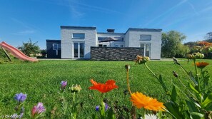 Experience a family-friendly home with a central entrance, large windows, and a well-maintained lawn.