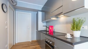 Una cocina moderna con electrodomésticos de acero inoxidable, suelo de madera y una planta en la encimera.