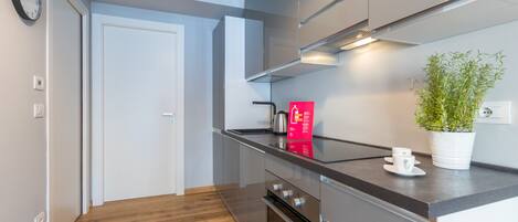 Een koelkast, een oven, een vaatwasser, kookgerei, borden en bestek