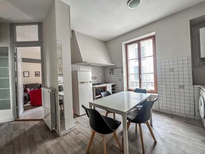 A modern kitchen with a dining area, a built-in stove, and a large window. - #EA | The Red Dormoy 🍓 (Grenoble)
