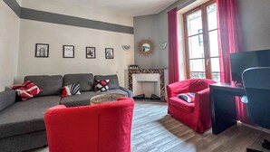 A living room with a grey sofa, red armchair, and a TV stand.