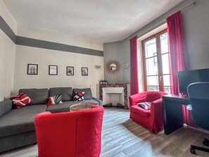 A living room with a grey sofa, red armchair, and a TV stand.