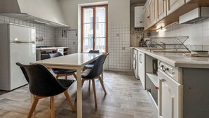 A modern kitchen with a dining table, chairs, and a window.