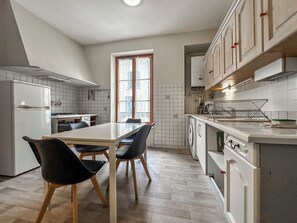 A modern kitchen with a dining table, chairs, and a window.