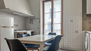 A kitchen with a dining table, chairs, a refrigerator, a stove, and a washing machine.