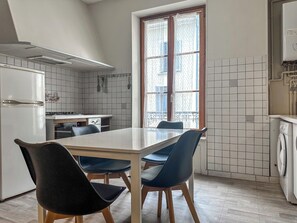 A kitchen with a dining table, chairs, a refrigerator, a stove, and a washing machine.