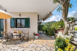 Une terrasse avec une table et des chaises, un pot de fleurs et une vue sur la verdure environnante.