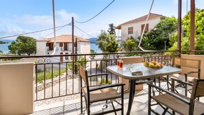 A balcony with a table, chairs, and a view of the sea and buildings. - Apartment "Nikoleta 1" with Sea View, Terrace & Wi-Fi (Lefkada)