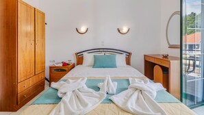 Een slaapkamer met een bed, een houten garderobe, nachtkastje en uitzicht door een glazen deur.