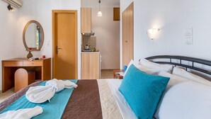 A hotel room with a bed, a desk, a mirror, a kitchenette, and a bathroom door. - Apartment "Nikoleta Studio 2" with Sea View, Terrace & Wi-Fi (Lefkada)