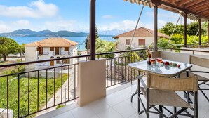 A balcony with a table, chairs, and a bottle of wine. - Apartment "Nikoleta Studio 2" with Sea View, Terrace & Wi-Fi (Lefkada)