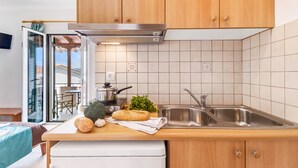 A modern kitchen with wooden cabinets, a stainless steel sink, and a view of the outdoors. - Apartment "Nikoleta Studio 2" with Sea View, Terrace & Wi-Fi (Lefkada)