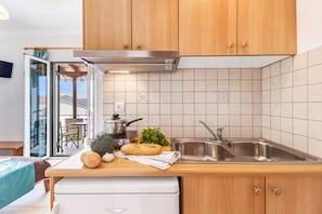 A modern kitchen with wooden cabinets, a stainless steel sink, and a view of the outdoors.