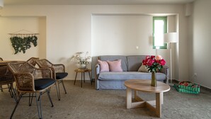 Ein Wohnzimmer mit einer Couch, Sesseln, einem Couchtisch, einer Lampe und einer Blumenvase.