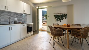 Eine moderne Küche mit weißen Schränken, einem eingebauten Backofen und einem Essbereich mit Korbstühlen und einem Holztisch.