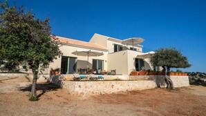 Ein modernes Haus mit Terrasse, Sitzgelegenheit im Freien und einem Baum.