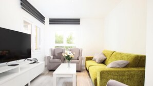 A modern living room with a flat-screen TV, a white coffee table, two sofas, and a window with blinds. - Holiday Apartment "Rieres" with Terrace & Wi-Fi (PORT POLLENÇA)