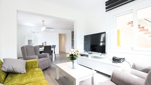A modern living room with a sofa, armchairs, a coffee table, a TV, and a vase with flowers. - Holiday Apartment "Rieres" with Terrace & Wi-Fi (PORT POLLENÇA)