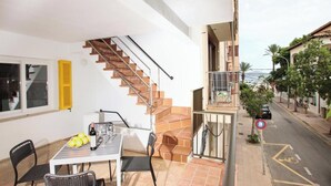 A residential property with a staircase, a balcony, a dining area with a table and chairs, and a view of the street. - Holiday Apartment "Rieres" with Terrace & Wi-Fi (PORT POLLENÇA)