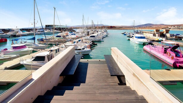 A marina with boats docked, a wooden walkway leading to the water, and a clear sky. - Vacation Home "Sol y Mar Caleta de Fuste" with Shared Pool, Garden & Wi-Fi (Caleta de Fuste)