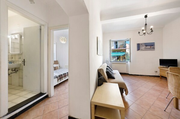 A modern living room with a sofa, a small table, a TV, and a window with a view of a balcony. - Apartment "Casa Federico" near the sea with balcony and Wi-Fi (Levanto)