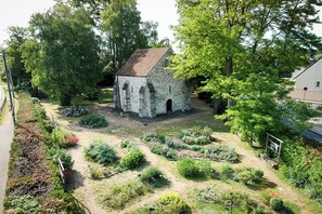 A small stone building surrounded by a garden with various plants and trees. - Nouveau ! Gîte à la Ferme en Forêt de Fontainebleau (Milly-la-Forêt)