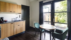 A modern kitchen with wooden cabinets, a black countertop, and a window with a view of greenery. - Zandvoort Lodge 1 - Amazing couples getaway! (Zandvoort)