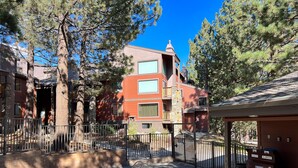 A residential area with a swimming pool, a fenced yard, and a multi-story building with a red facade. - Pet-Friendly & Updated. Modern Décor, Bright. On-Site Pool & Tennis Courts (Mammoth Lakes)