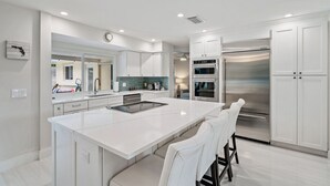 A modern kitchen with white cabinetry, a large island, stainless steel appliances, and recessed lighting. - Luxurious Pool Home Central to Everything! (Palm Beach Gardens)