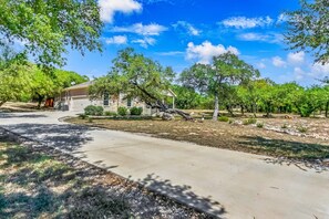A residential property with a paved driveway, a detached house, and a well-maintained lawn with trees.