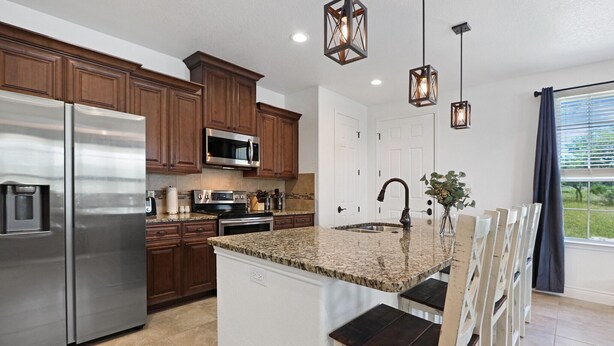 A modern kitchen with stainless steel appliances, granite countertops, and wooden cabinets.