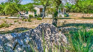 A stone marker with the number 1608, a house with a stone facade, and a tree in the foreground.