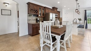 A modern kitchen with wooden cabinets, a central island, and white chairs.