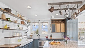 A kitchen with wooden shelves, hanging pots, a stove, and a window with a view. - BACKYARD WANDERLAND - Near ARK & Creation Museum - perfect for big families! (Burlington)