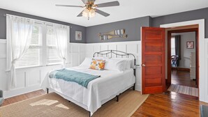 A bedroom with a bed, a ceiling fan, a wooden door, and a window with curtains. - BACKYARD WANDERLAND - Near ARK & Creation Museum - perfect for big families! (Burlington)