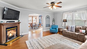 A living room with a fireplace, television, ceiling fan, and a dining area in the background. - BACKYARD WANDERLAND - Near ARK & Creation Museum - perfect for big families! (Burlington)