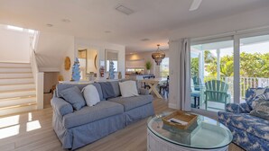 Amplia sala de estar con sofá, una mesa de centro de vidrio y vistas al exterior.