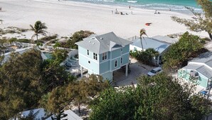 Una propiedad frente al mar con una casa de dos pisos, una piscina y vista a la playa.