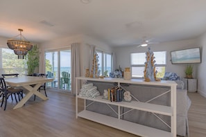 Un salon moderne avec une table à manger, une console blanche et une grande fenêtre offrant une belle vue.