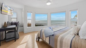 A bedroom with a bed, a desk, and a chair, large windows with a beach view, and a ceiling fan. - Turtle Beach: 2 Homes, Sleeps 10, Gulf Front with 2 Pools! (Holmes Beach)