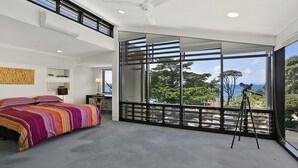 A bedroom with a large window, a bed with colorful bedding, a desk, and a telescope. - Cetacea - Point Lonsdale (POINT LONSDALE)