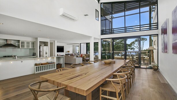 A spacious kitchen with a long wooden table, a dining area with chairs, and a view of the sea through large windows. - Cetacea - Point Lonsdale (POINT LONSDALE)