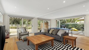 Amplia sala de estar con un sofá gris, dos mesitas de madera y un tapete a rayas.