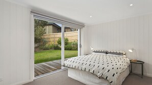 Un dormitorio con un gran ventanal corredera que da a un jardín trasero.