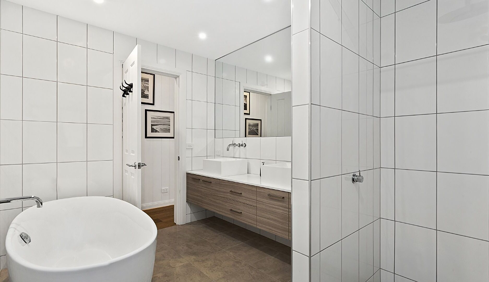 A modern bathroom with a freestanding bathtub, a vanity with a mirror, and tiled walls.