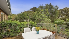 A patio with a white table and chairs, surrounded by potted plants and a metal fence.