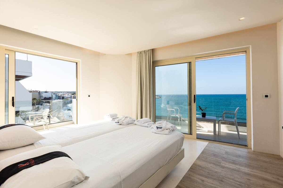Habitación de hotel con balcón, cama y vista al mar.
