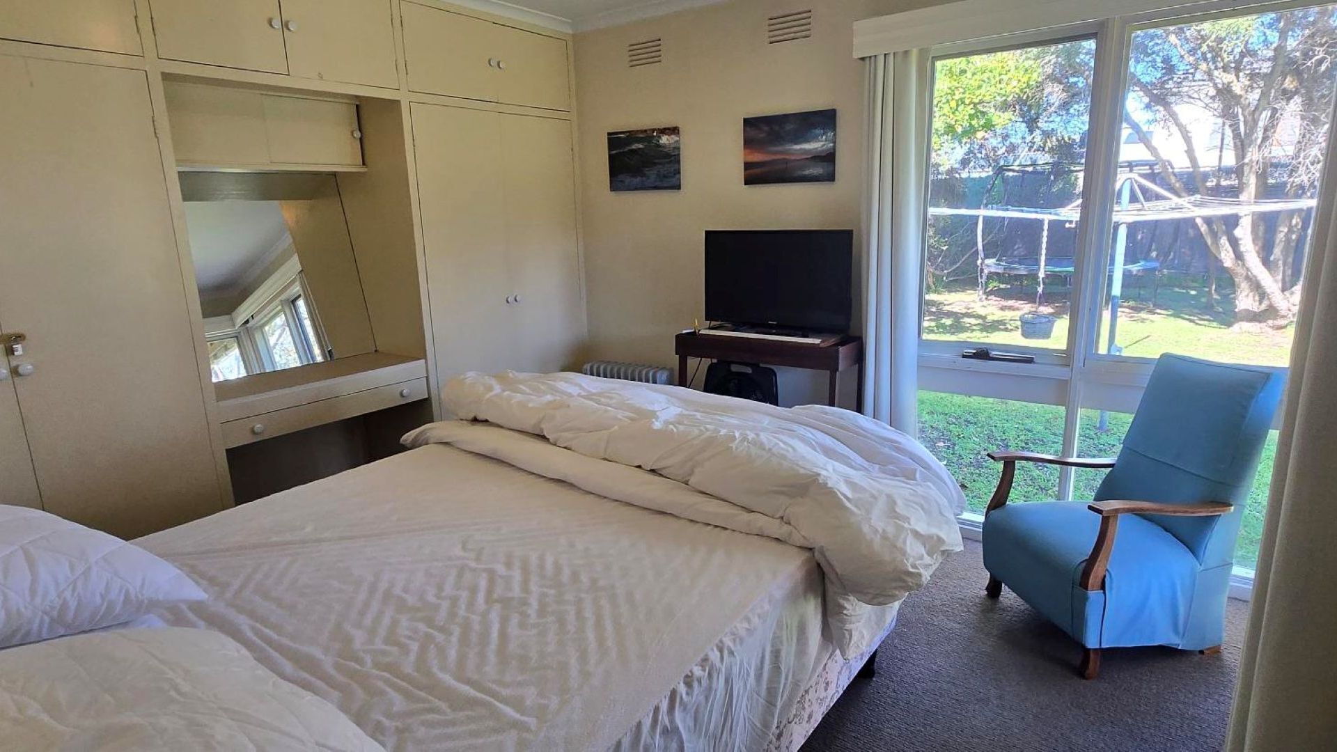 A hotel room with two beds, a television, and a chair.